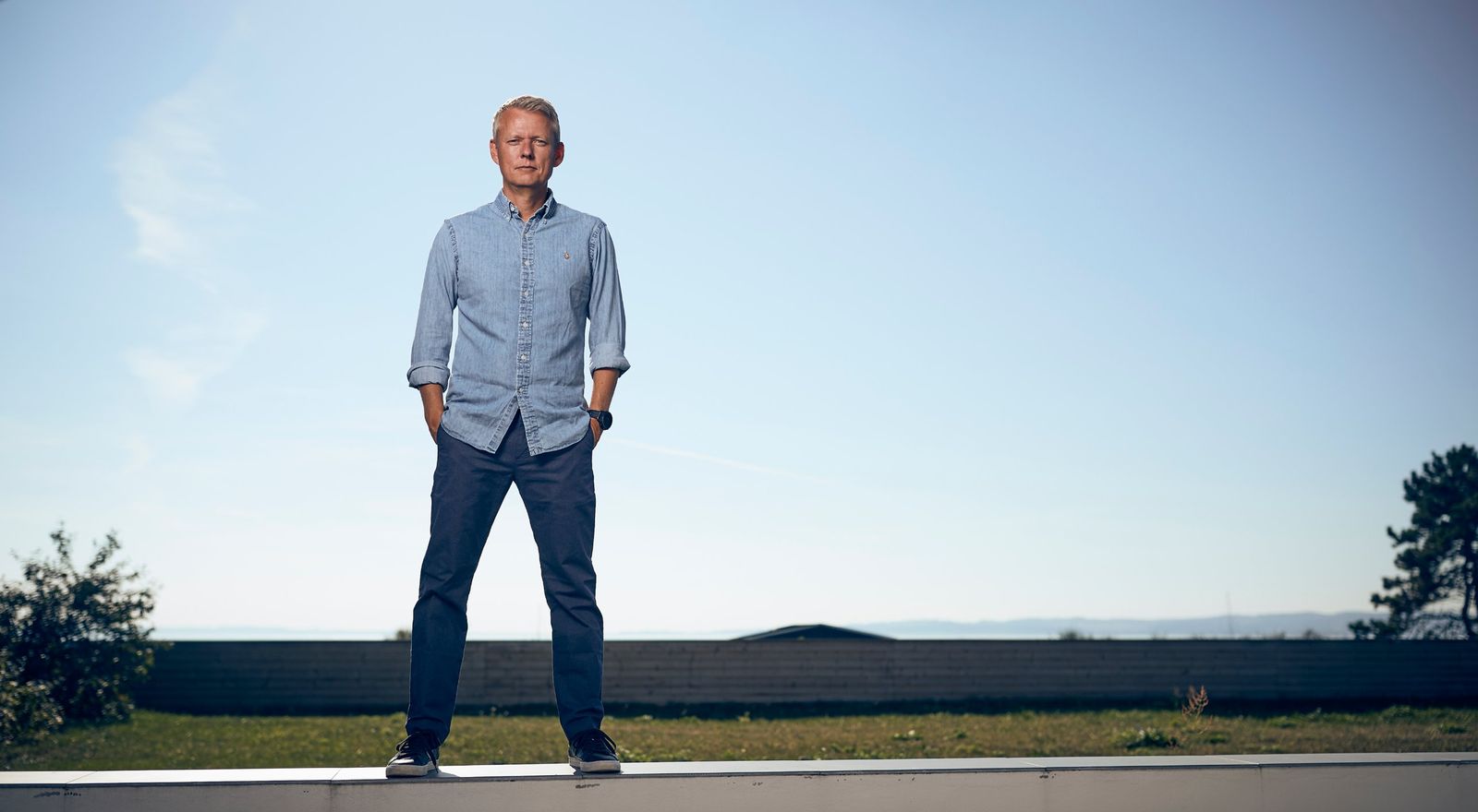 Martin Nymann Vinther står på en mur foran en klar himmel